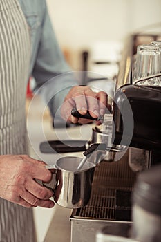 Barista making coffee near the coffee machine.