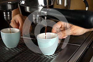 Barista making espresso using professional coffee machine, closeup