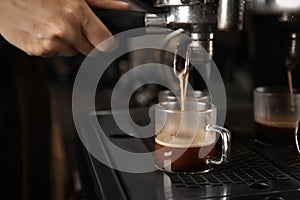 Barista making espresso using professional coffee machine, closeup