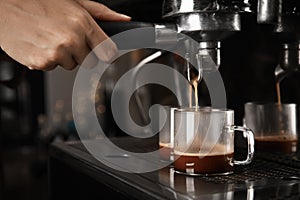 Barista making espresso using professional coffee machine, closeup