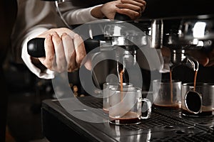 Barista making espresso using professional coffee machine, closeup