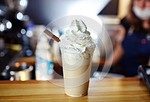 Barista making frappe - iced latte coffee with caramel and chocolate syrup and whipped cream