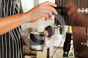 Barista making milk froth to pun in cappuccino coffee