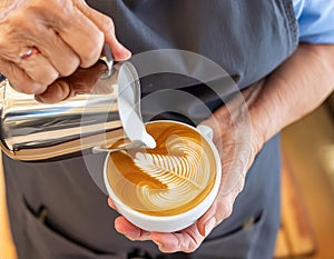 A barista perfecting latte art, pouring creamy froth into a cup of coffee photo