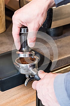 Barista placing tamper over coffee in portafilter to making espresso