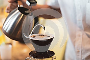 Barista pour hot water to ground coffee on dripper