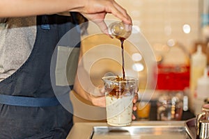 Barista pouring coffee to takeaway cup to making iced coffee latte in the cafe.