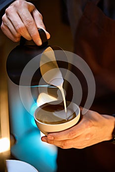 Barista pouring froth milk in coffee making caffe latte art serve to customer