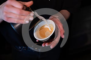 Barista pouring latte foam on coffee, espresso. creating a perfect latte art. dark colours, coffee house