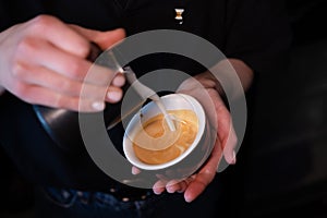 Barista pouring latte foam on coffee, espresso. creating a perfect latte art. dark colours, coffee house