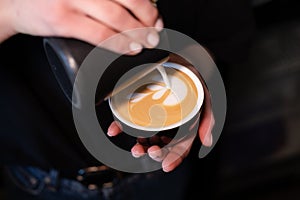 Barista pouring latte foam on coffee, espresso. creating a perfect latte art. dark colours, coffee house