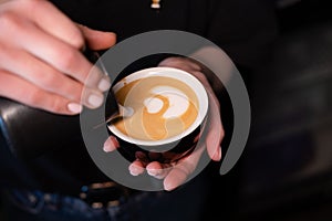 Barista pouring latte foam on coffee, espresso. creating a perfect latte art. dark colours, coffee house