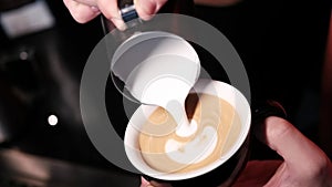 Barista pouring latte foam on coffee, espresso. creating a perfect latte art. dark colours, coffee house. slow motion