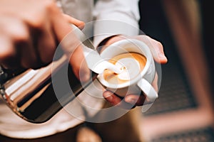 Barista pouring latte foam over coffee, espresso and creating a perfect cappuccino