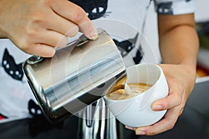 Barista pouring milk in capuccino coffee photo