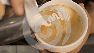Barista pouring milk in coffee and making cappuccino foam with heart close up