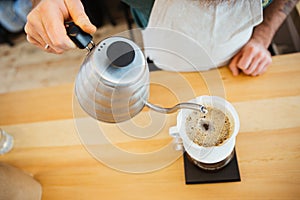 Barista pouring water on coffee ground with filter