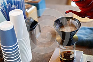 Barista pouring water over ground coffee beans contained in a filter