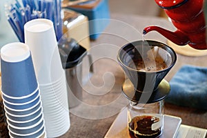 Barista pouring water over ground coffee beans contained in a filter