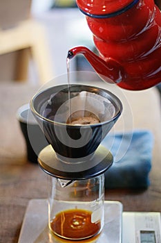 Barista pouring water over ground coffee beans contained in a filter