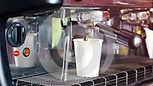 Barista prepares fresh coffee on a coffee machine in a paper white glass.