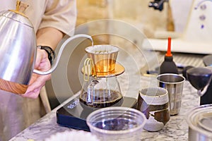 barista preparing coffee with drip coffee and drop the water on coffee ground with filter