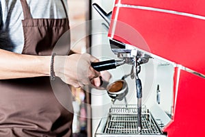 Barista preparing coffee on portafilter machine in cafe