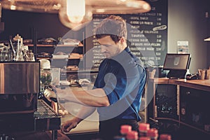 Barista preparing cup of coffee for customer in coffee shop.