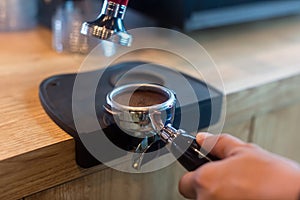 Barista pressing coffee in the machine holder. Coffee powder on coffee tamper. barista using tamper to press ground coffee into po