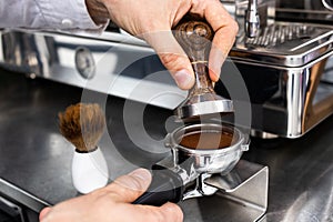 Barista pressing ground coffee into portafilter with a tamper.