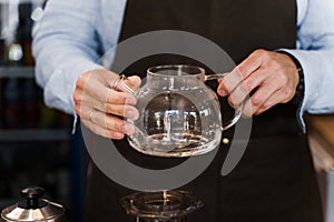 Barista rotates in hands and looks at the pot with coffee before making aeropress. Coffee brewing process. Scandinavian
