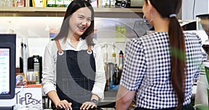 Barista serving customer and Woman is paying for coffee by credit card in coffee shop