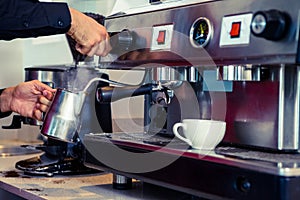 Barista steaming milk at the coffee machine