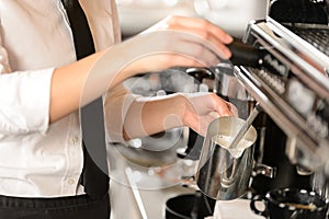 Barista steaming milk for hot cappuccino