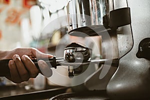 barista use bottomless filter with grinder machine at coffee shop. coffee maker concept