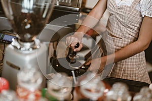 Barista using a tamper to press ground coffee into a portafilter. Coffee maker concept