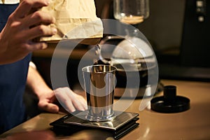 Barista weighs coffee on scales before preparing espresso