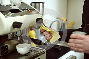 Barista wipes out leftover drops of milk on coffee machine