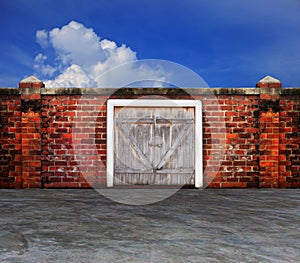 Bark panel wood barn door on old brick wall with blue sky behin