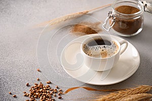 Barley coffee in white cup and ears of barley on gray background.