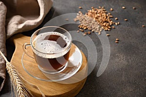 Barley coffee in white cup and ears of barley on brown background.