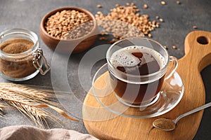 Barley coffee in white cup and ears of barley on brown background.