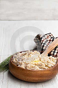 Barley groats porridge in wooden bowl on white table
