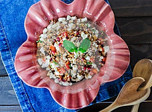 Barley salad with pomegranate, feta and mint on a pink ceramic and denin napkin photo