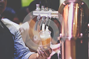 Barman or bartender pouring a beer from beer tap