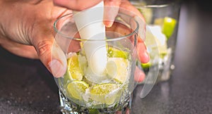 Barman crushes green lemons with a pill to make caipirihnas