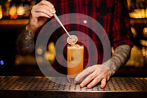 Barman decorating fresh orange lemonade cocktail with a slice of