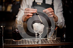 Barman decorating two cocktail glasses with cherries