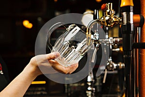 Barman going to pour beer into glass goblet from tap