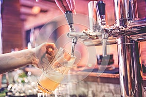 Barman hand at beer tap pouring a draught lager beer at restaurant, pub or bistro